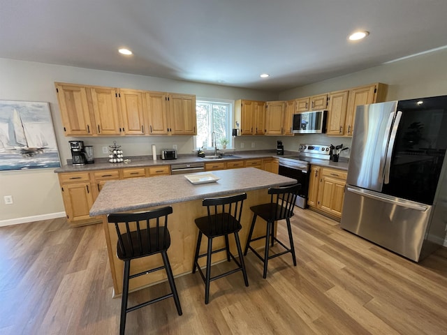 kitchen featuring a breakfast bar, appliances with stainless steel finishes, a center island, and sink