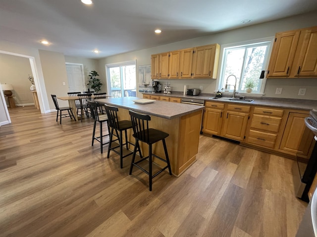 kitchen with a breakfast bar, sink, a center island, light hardwood / wood-style flooring, and light brown cabinets