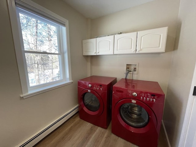 clothes washing area with a baseboard heating unit, hardwood / wood-style floors, cabinets, and washing machine and clothes dryer