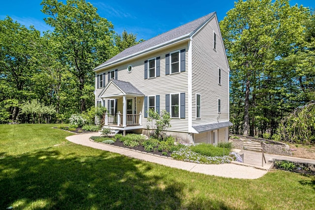 colonial inspired home with a garage, a front yard, and a shingled roof