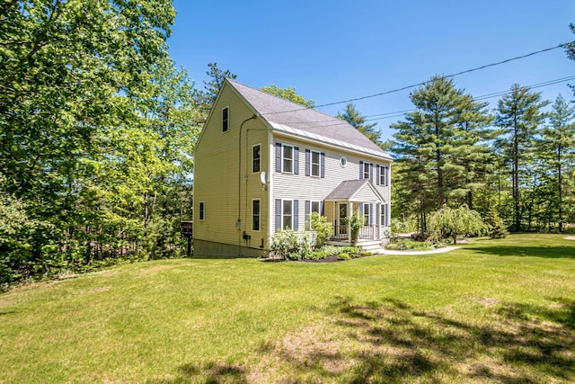 view of front of house featuring a front lawn and a shingled roof