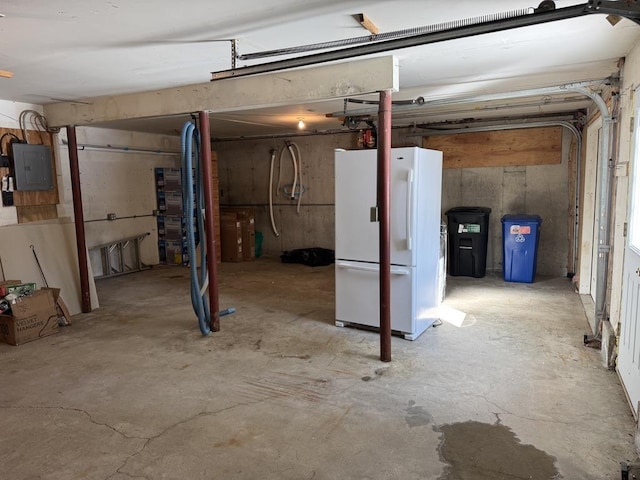 basement featuring electric panel and white fridge