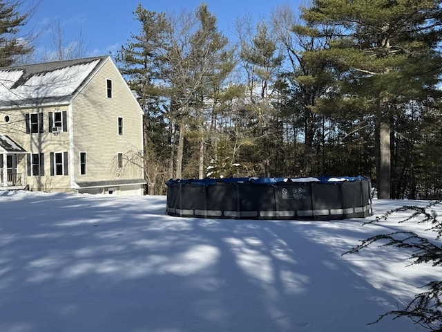 snow covered property with a covered pool