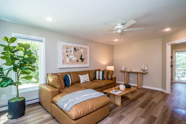 living room with baseboard heating, ceiling fan, and wood-type flooring