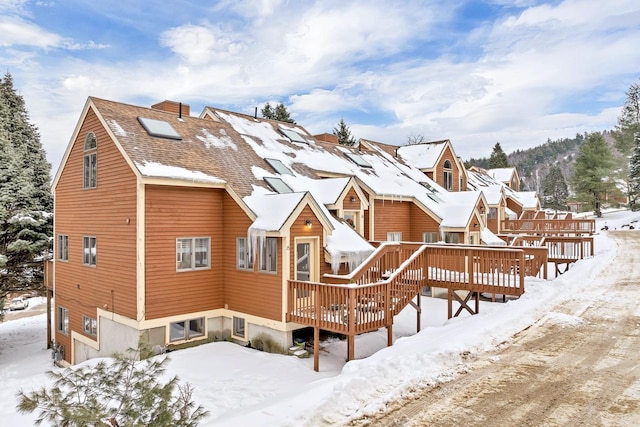 snow covered rear of property with a deck