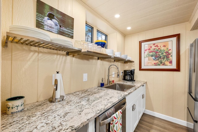 kitchen featuring appliances with stainless steel finishes, wood-type flooring, sink, light stone counters, and crown molding