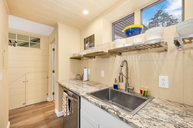 kitchen featuring dishwasher, sink, light stone countertops, and light wood-type flooring