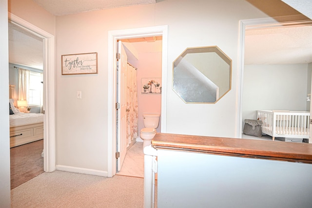 hallway featuring light carpet and a textured ceiling