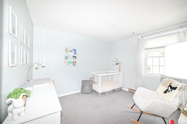 carpeted bedroom with sink and a nursery area