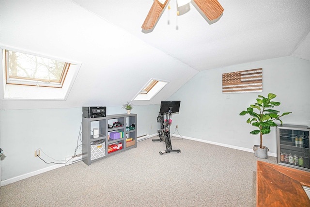 exercise area with carpet, heating unit, vaulted ceiling with skylight, and ceiling fan