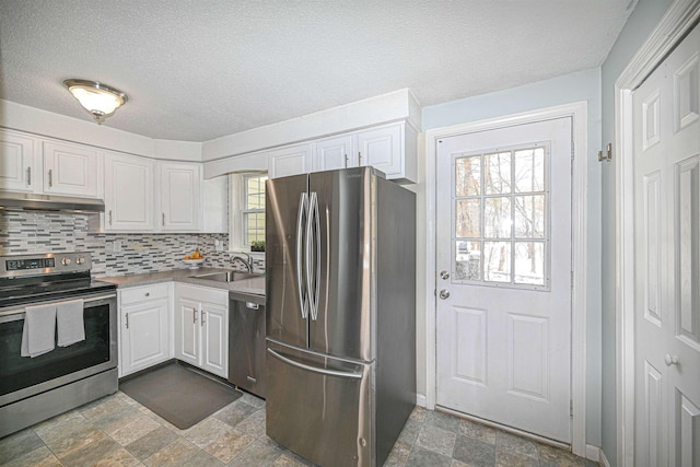 kitchen with sink, white cabinetry, a textured ceiling, appliances with stainless steel finishes, and decorative backsplash