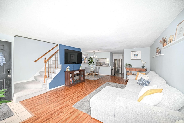 living room featuring an inviting chandelier, wood-type flooring, and a textured ceiling