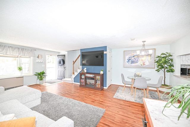 living room with radiator heating unit, light hardwood / wood-style floors, and a textured ceiling