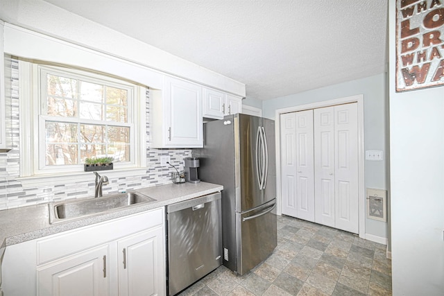 kitchen featuring sink, backsplash, stainless steel appliances, white cabinets, and a textured ceiling