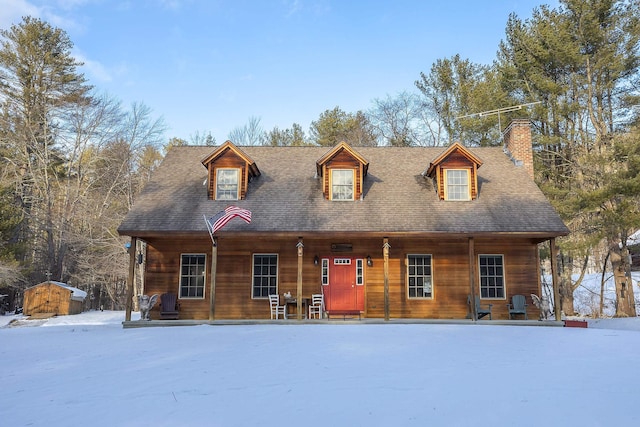 new england style home featuring covered porch and a storage unit