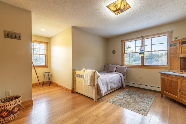 bedroom featuring a baseboard radiator, a textured ceiling, and light hardwood / wood-style flooring