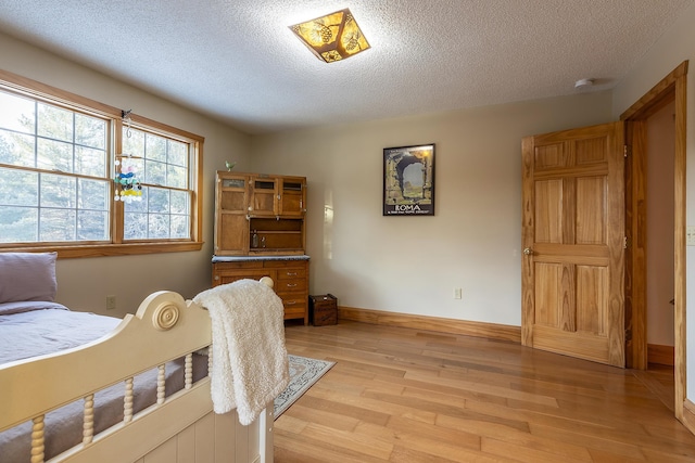 bedroom featuring light hardwood / wood-style floors and a textured ceiling