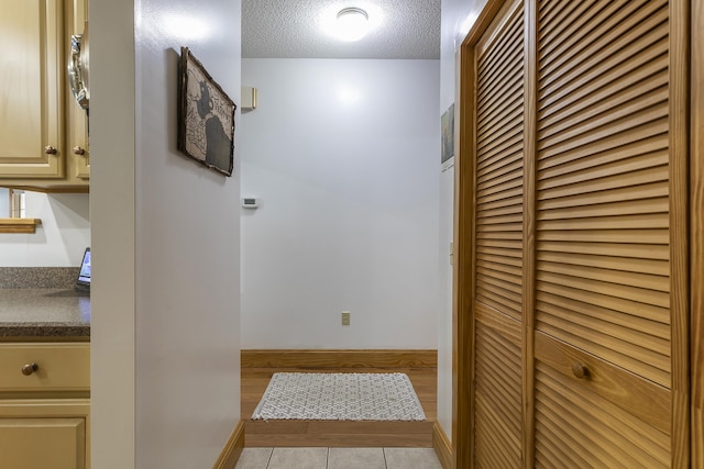 corridor with light tile patterned flooring and a textured ceiling