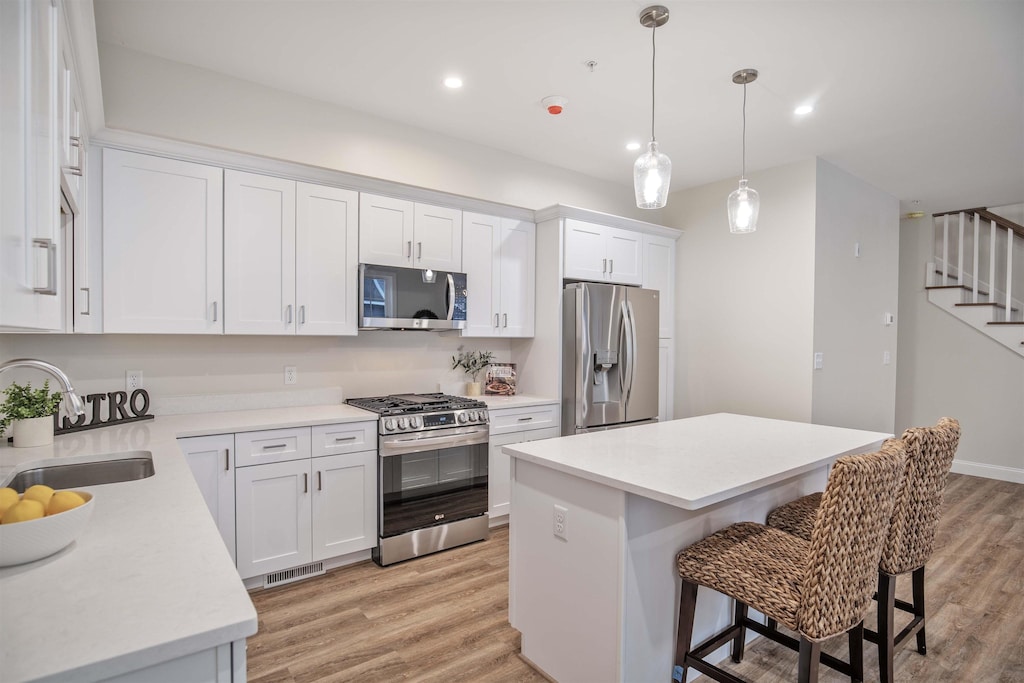 kitchen featuring sink, stainless steel appliances, a center island, and white cabinets