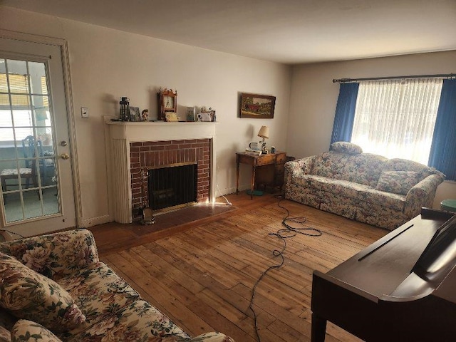 living room featuring hardwood / wood-style flooring and a brick fireplace