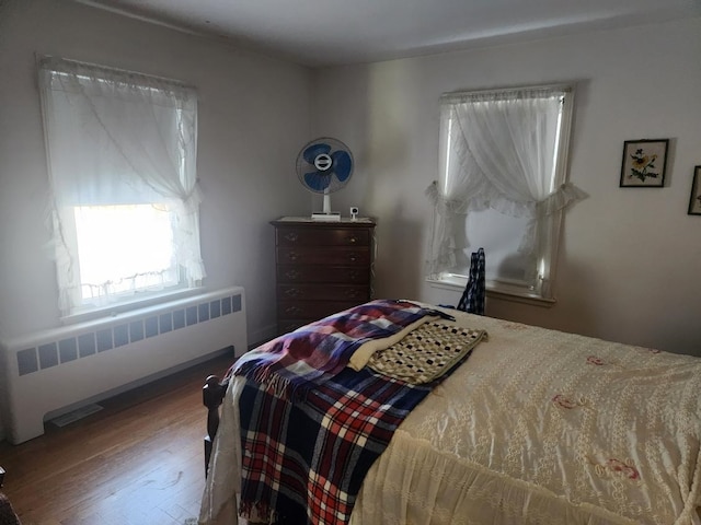 bedroom with radiator and hardwood / wood-style floors