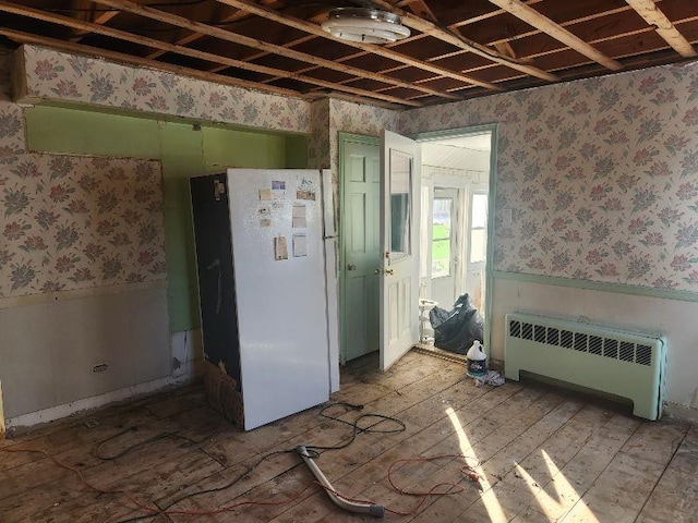 kitchen with radiator heating unit, green cabinets, and white fridge