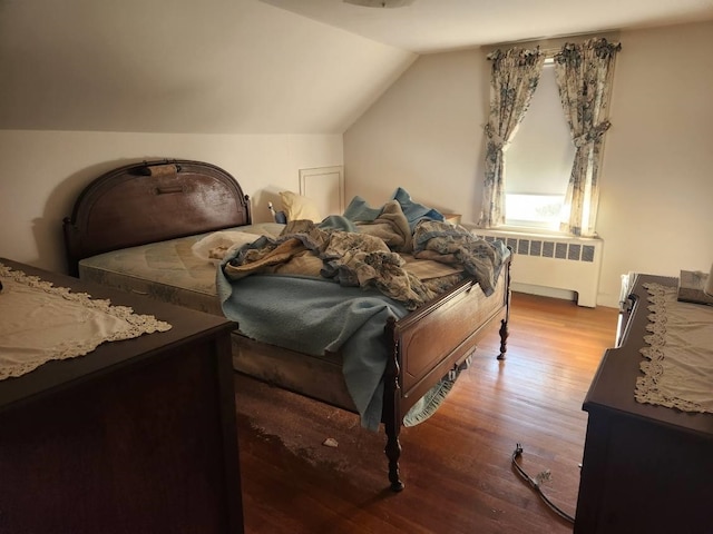 bedroom featuring lofted ceiling, radiator, and hardwood / wood-style floors