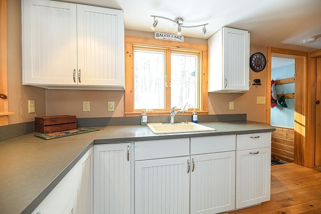 kitchen with hardwood / wood-style flooring, white cabinetry, and sink