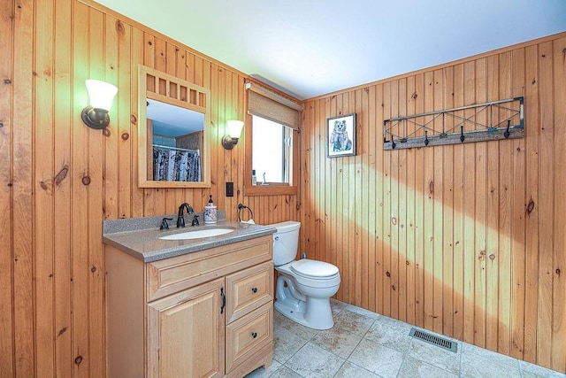 bathroom with wooden walls, vanity, and toilet