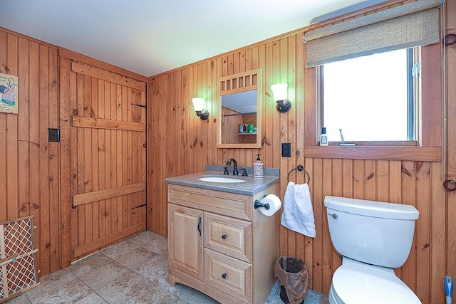 bathroom with vanity, toilet, and wood walls