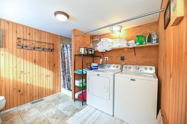 laundry room with washer and clothes dryer and wooden walls