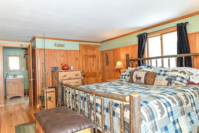 bedroom featuring sink, crown molding, wooden walls, and light wood-type flooring