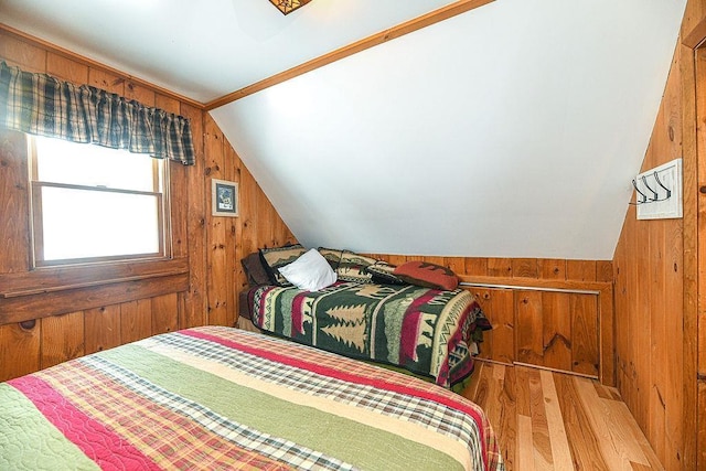 bedroom with hardwood / wood-style flooring, wooden walls, and vaulted ceiling