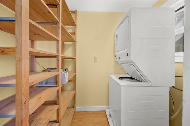 laundry room with light wood-type flooring and stacked washing maching and dryer