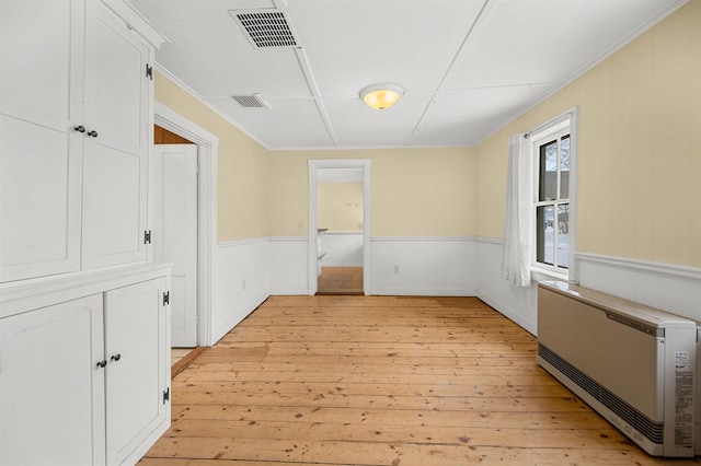 interior space with crown molding, heating unit, and light hardwood / wood-style floors