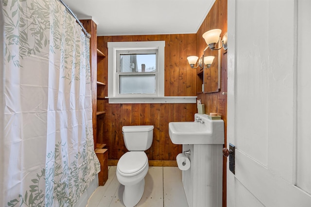 bathroom featuring a shower with shower curtain, toilet, and wood walls