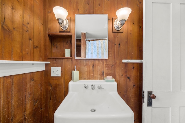 bathroom featuring sink and wood walls