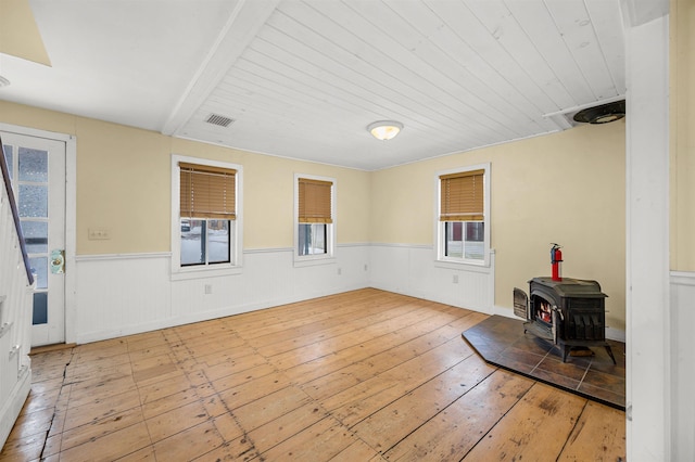 interior space with wood ceiling, a wood stove, and light wood-type flooring