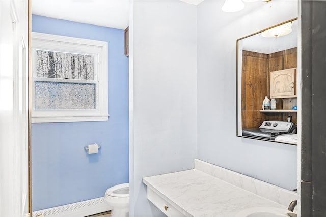 bathroom with washing machine and clothes dryer, vanity, toilet, and a baseboard radiator