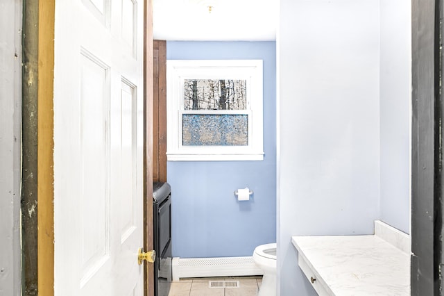 bathroom with tile patterned flooring, a baseboard heating unit, and toilet