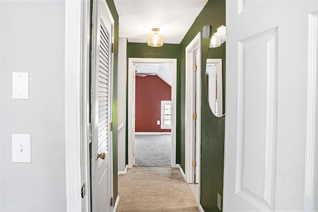 hallway featuring vaulted ceiling and light colored carpet