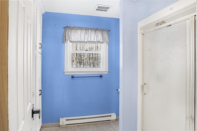 bathroom with an enclosed shower, a baseboard heating unit, and tile patterned floors