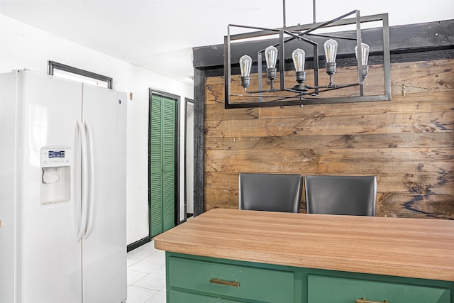 kitchen with green cabinetry, light tile patterned floors, and white fridge with ice dispenser