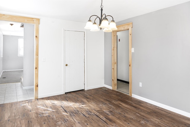 unfurnished bedroom with hardwood / wood-style flooring, an inviting chandelier, and a closet