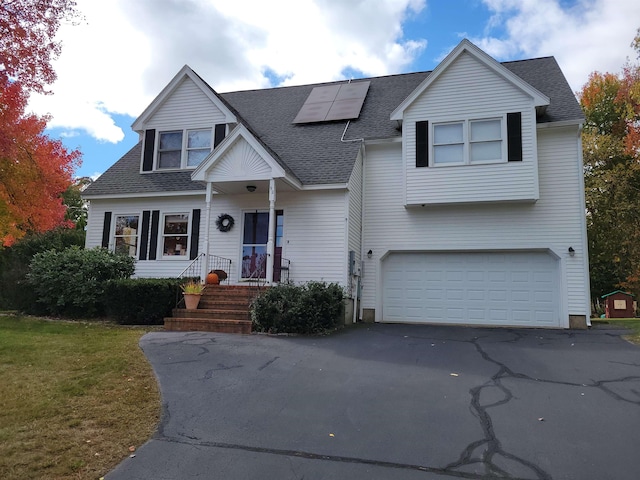 view of front of house featuring a garage, a front lawn, and solar panels