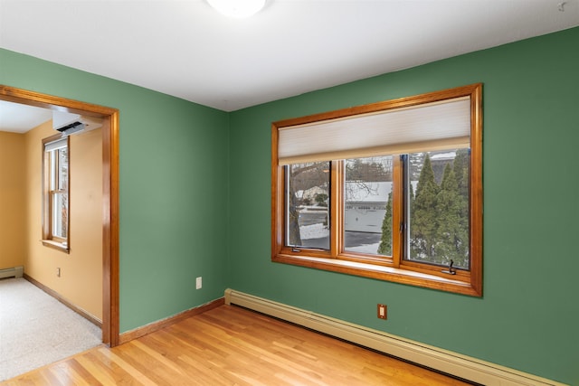 unfurnished room featuring wood-type flooring and a baseboard heating unit