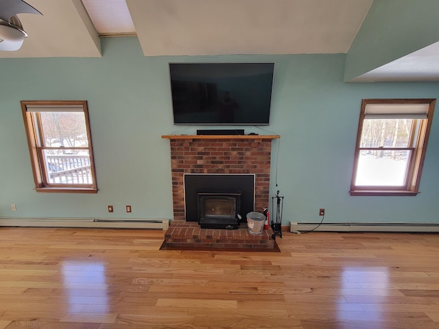 living room with a wood stove, light hardwood / wood-style floors, and baseboard heating