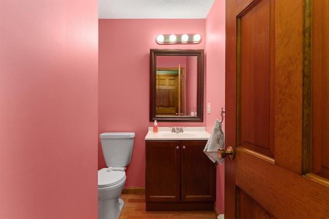 bathroom with vanity, wood-type flooring, and toilet