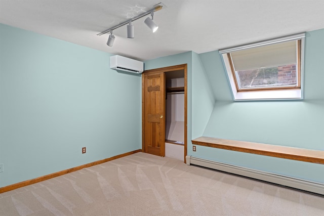 unfurnished bedroom with an AC wall unit, a skylight, track lighting, baseboard heating, and light carpet