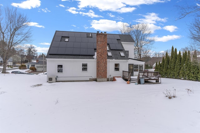 snow covered property featuring a deck and solar panels